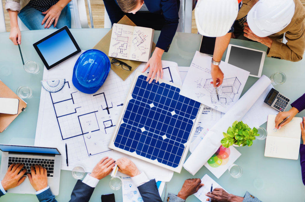 A group of people sitting around a table with some solar panels.
