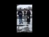 Three people standing in the snow holding a stick.