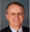 A man in suit and glasses smiling for the camera.