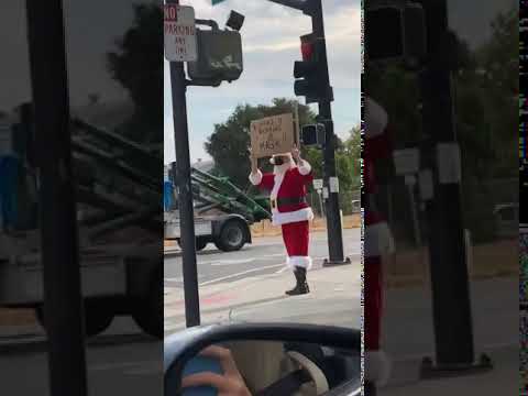 A man dressed as santa claus holding up a sign.