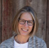 A woman with glasses smiling for the camera.