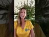 A woman in yellow shirt standing next to tree.