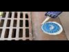 A blue and white sign sitting on the ground next to a grate.