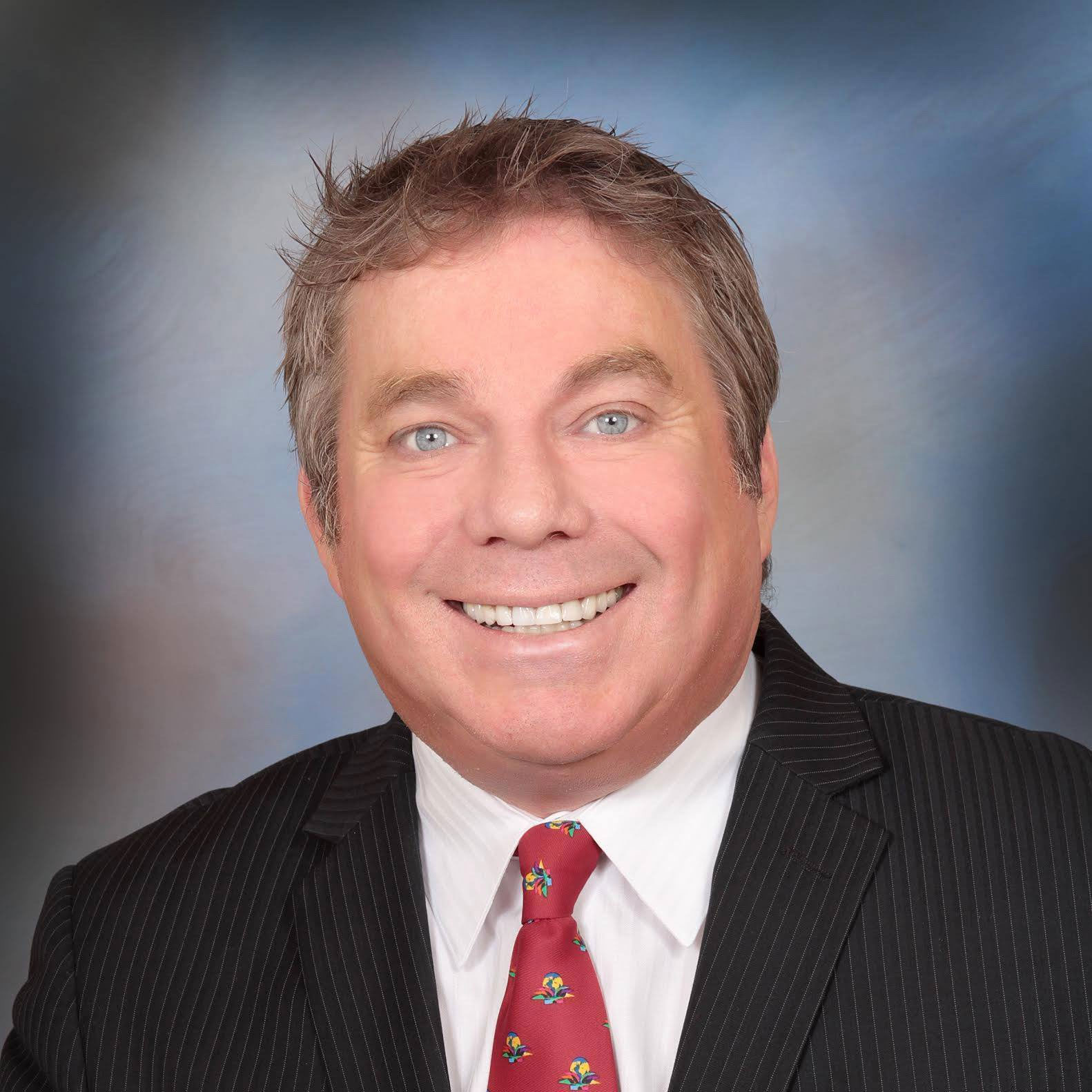 A man in suit and tie smiling for the camera.