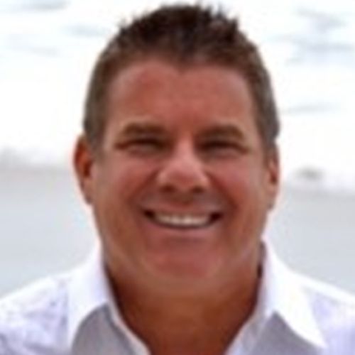 A man with spiky hair and white shirt smiling.