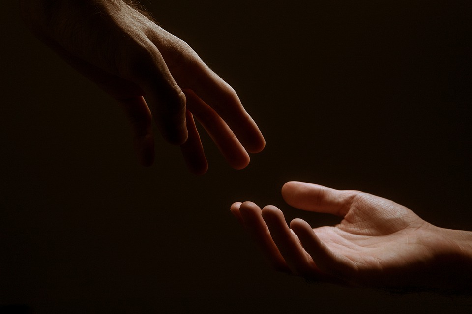 Two hands reaching out to each other in the dark.